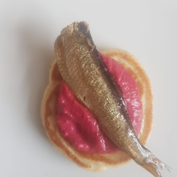 Smoked Sprats served on a Ballini with Horse Raddish and Beetroot Cream